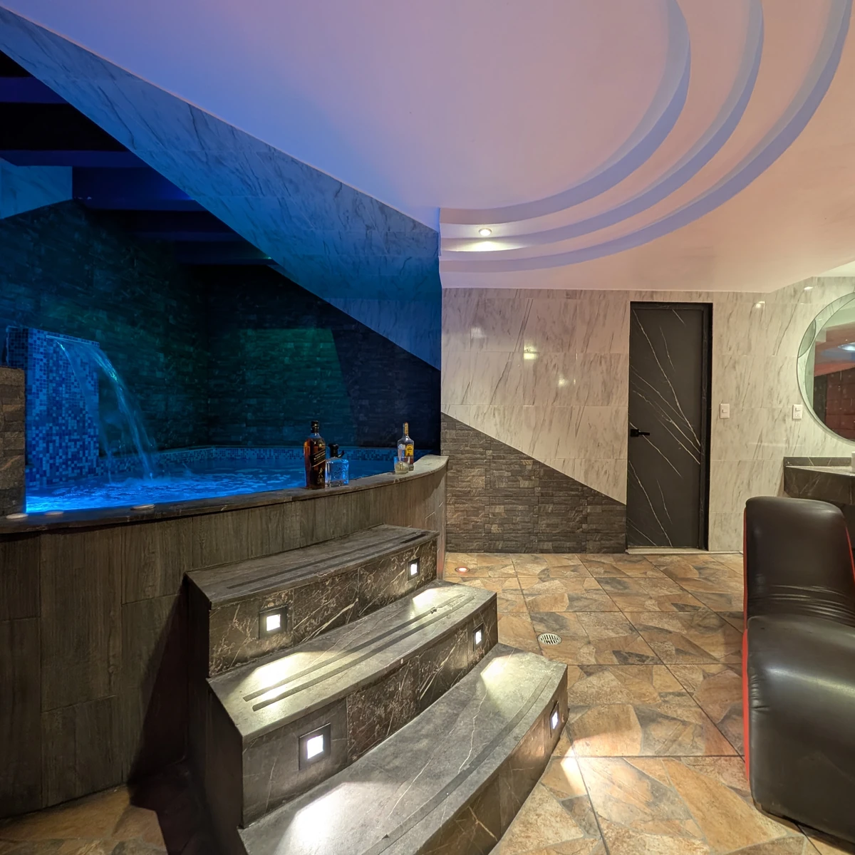 Alberca iluminada y cascada en una suite privada